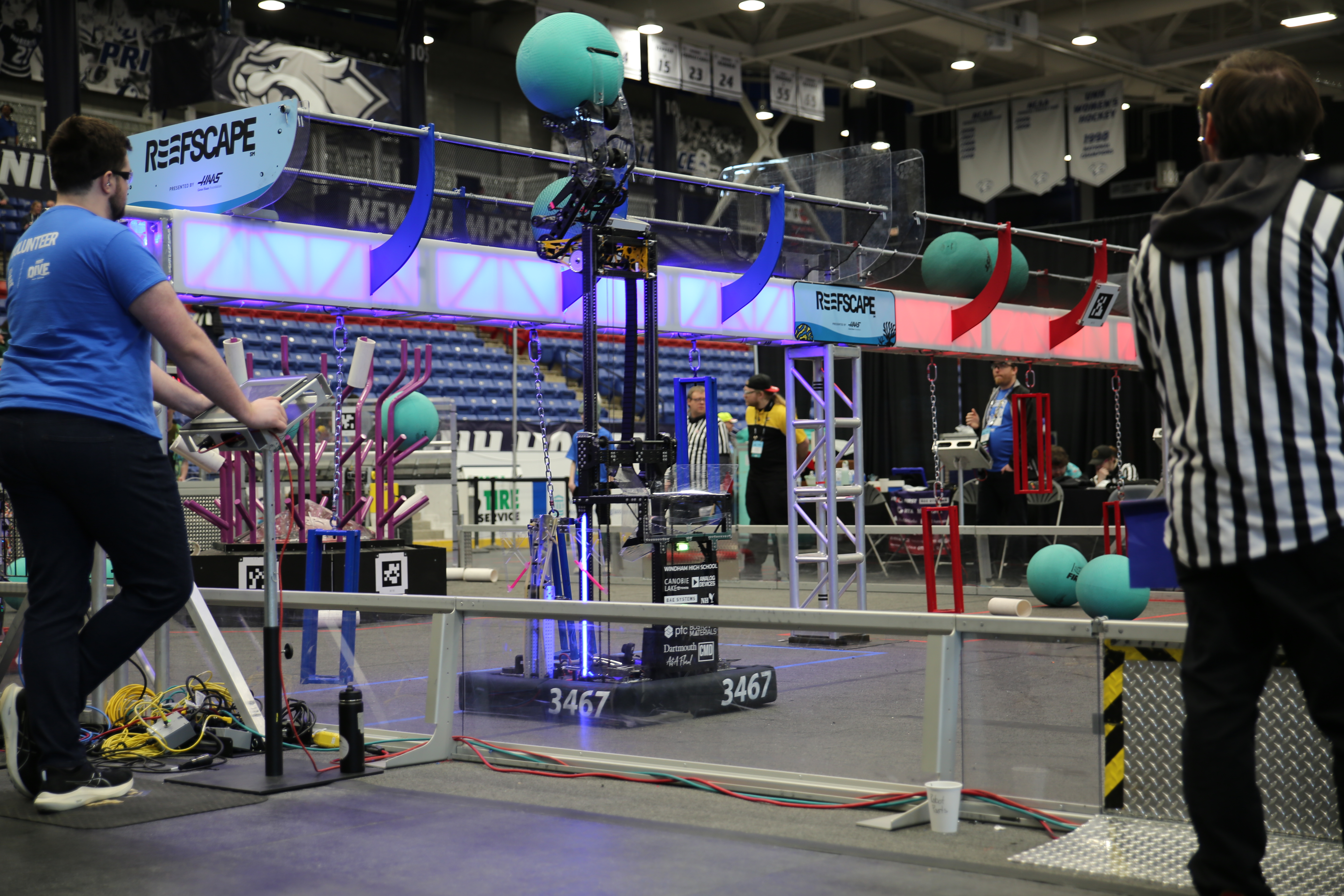 Sleek robot with elevator extended upwards, placing blue ball into a net